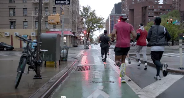 A group of people are running down a street in the rain.