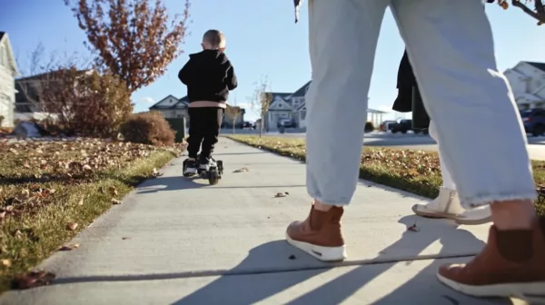 A young boy is riding a skateboard on a sidewalk.