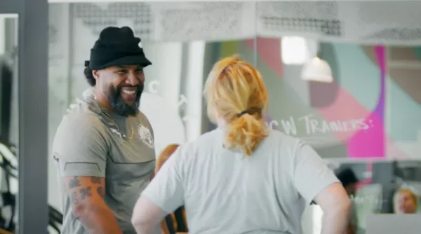 A man with a beard is talking to a woman in a gym.