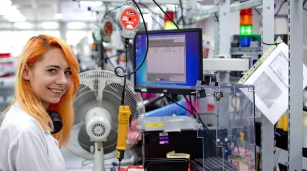 A woman working in a factory with orange hair.