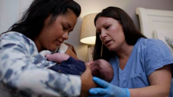 Two women are holding a baby in their arms.