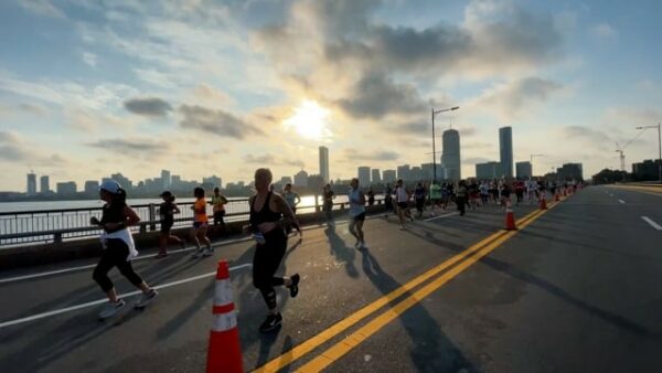 A group of people running a marathon in front of a city skyline.