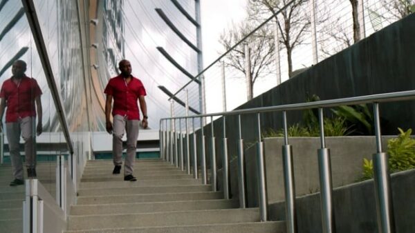 A man in a red shirt is walking down a set of stairs.